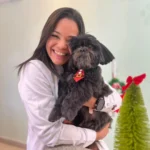 Integrante da equipe da Pet Villa abraçando um shih tzu preto