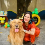 Integrante da equipe da Pet Villa agachada com um golden retriever na área de recreação