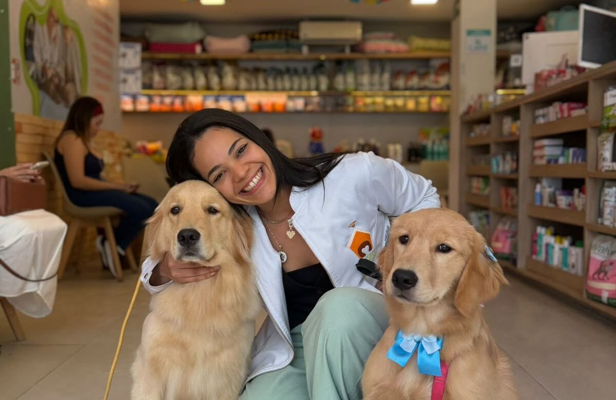 Médica-veterinária da Pet Villa sorrindo ao lado de dois golden retrievers dentro da loja