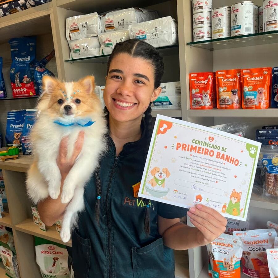 Integrante da Pet Villa segurando um filhote e o certificado de primeiro banho